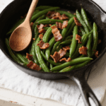 The recipe combines green beans and bacon with garlic, onions, brown sugar, and a bourbon splash. Preparing green beans on the stovetop provides a fast method for cooking vegetables, with the process taking only 20 minutes for optimal results. This dish functions as a straightforward green bean side option for Thanksgiving, Christmas, or other holiday meals.